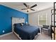 Bedroom with blue accent wall, ceiling fan and grey chair near the shelving at 61 N Auburn Landing Pl, Auburn, GA 30011