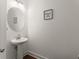 Modern powder room with a pedestal sink, round mirror, and a decorative wall sign at 61 N Auburn Landing Pl, Auburn, GA 30011