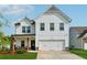 Charming two-story white farmhouse with a well-manicured lawn and a two-car garage at 701 Woodward Ct, Canton, GA 30114