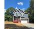 Two-story home with navy siding, white trim, a red porch, an attached two car garage and nice landscaping at 102 Neal Ave, Stockbridge, GA 30281