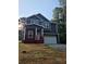 Two-story home with navy siding, white trim, a red porch, an attached two car garage and nice landscaping at 102 Neal Ave, Stockbridge, GA 30281