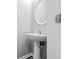 Close-up of a pedestal sink and round mirror in a half bathroom at 930 Silver Lake Dr, Acworth, GA 30102