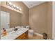 Half bath featuring white marble countertop, wood cabinetry, decorative mirror and vanity lighting at 11575 Wildwood Springs Dr, Roswell, GA 30075