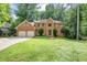 Stately brick home featuring a two-car garage and lush green lawn at 11575 Wildwood Springs Dr, Roswell, GA 30075