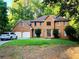 Charming brick home featuring an attached two-car garage, lush lawn, and mature trees at 11575 Wildwood Springs Dr, Roswell, GA 30075