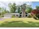 Ranch-style house with a stone chimney, a two-car garage and well-manicured lawn and mature landscaping at 297 Northgate Trce, Roswell, GA 30075