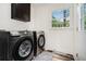 Bright laundry room with front load washer and dryer, overhead cabinets, and a large window at 2674 Skylane Dr, Marietta, GA 30062