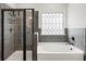 Modern bathroom featuring a glass-enclosed shower, soaking tub, and decorative window at 191 Madison Bnd, Woodstock, GA 30188