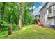 Large, wooded backyard with green grass and a screened-in porch with stairs to the yard at 241 Tweed Ct, Sugar Hill, GA 30518