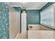 Bathroom with shower, large tub, storage cabinet and floral wallpaper at 241 Tweed Ct, Sugar Hill, GA 30518