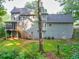 Exterior rear view of a two-story house with a screened in porch and lush, wooded backyard at 241 Tweed Ct, Sugar Hill, GA 30518
