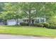Well-manicured lawn and mature trees frame this residence creating a peaceful ambiance at 241 Tweed Ct, Sugar Hill, GA 30518