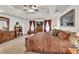 This is a bright carpeted main bedroom with tray ceilings and plenty of furniture and natural light at 241 Tweed Ct, Sugar Hill, GA 30518