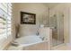 Bright bathroom featuring separate tub, shutters and frameless glass shower at 5029 Rosalie Rd, Johns Creek, GA 30022