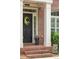 Charming brick home entrance featuring a black door with decorative wreath and manicured landscaping at 5029 Rosalie Rd, Johns Creek, GA 30022