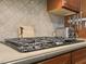 Close up of a cooktop in a kitchen featuring granite countertops and tile backsplash at 895 Mill Garden Pl, Cumming, GA 30040