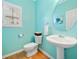 Well-lit half bath featuring a pedestal sink, toilet, round mirror, and a bright turquoise color palette at 977 Frog Leap Trail Nw, Kennesaw, GA 30152