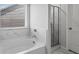 Bright bathroom showcasing a soaking tub with marble surround and a glass-enclosed shower at 49 Ryder Pass Way, Loganville, GA 30052