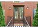 Close-up of a beautiful double-door entry with brick surround, stylish sconces and a 'welcome' mat at 530 Summerhill Dr, Roswell, GA 30075