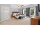 A spacious main bedroom featuring a tray ceiling, carpeted floors and natural light from three windows at 530 Summerhill Dr, Roswell, GA 30075