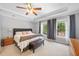 A well-lit main bedroom offers a tray ceiling, ceiling fan, and large windows with backyard views at 530 Summerhill Dr, Roswell, GA 30075