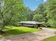 Ranch-style home featuring a well-manicured lawn, mature trees, and a long driveway with a covered carport at 415 Haven Ln, Marietta, GA 30066