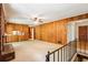 Spacious living room featuring wood paneling, brick fireplace, carpet, and staircase at 415 Haven Ln, Marietta, GA 30066