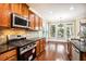 A kitchen features wooden cabinetry, granite countertops, stainless steel appliances, and a breakfast nook with bright windows at 189 Privet Cir, Suwanee, GA 30024