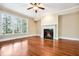 A living room with a fireplace, wood floors, a ceiling fan, and windows at 189 Privet Cir, Suwanee, GA 30024