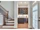 Elegant dry bar with custom cabinetry, wine cooler, and stylish glass shelving adjacent to the hardwood stairs at 255 Wembley Cir, Atlanta, GA 30328