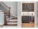 Elegant dry bar with custom cabinetry, wine cooler, and stylish glass shelving adjacent to the hardwood stairs at 255 Wembley Cir, Atlanta, GA 30328