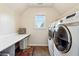 Bright laundry room featuring modern washer and dryer, storage shelf, and folding table at 302 Shawnee Indian Ln, Suwanee, GA 30024