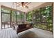 Relaxing screened porch featuring a swing, ceiling fan, and views of lush greenery at 302 Shawnee Indian Ln, Suwanee, GA 30024