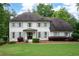 Two-story white brick home with manicured lawn, mature landscaping, grey shutters, and a classic, symmetrical design at 3600 Morishop Nw Cv, Marietta, GA 30064