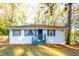 Quaint one-story house with blue trim, white brick exterior, front yard and surrounded by trees at 3182 Latona Sw Dr, Atlanta, GA 30354
