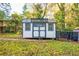 White shed with gray trim and a metal roof, offering storage and workshop potential in a private backyard at 3182 Latona Sw Dr, Atlanta, GA 30354