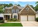 Traditional two-story brick home featuring a two-car garage, symmetrical design and manicured landscaping at 12554 Huntington Trce, Alpharetta, GA 30005
