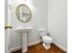 Powder room featuring a pedestal sink, oval mirror with gold frame, and wood flooring at 12554 Huntington Trce, Alpharetta, GA 30005