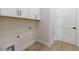 Well-lit laundry area with white cabinets, modern appliances and wood-style flooring at 160 South Village Ave, Holly Springs, GA 30115