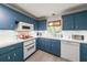 Traditional kitchen featuring painted blue cabinets, white appliances, and lots of counter space for meal preparation at 2889 Mount Olive Dr, Decatur, GA 30033