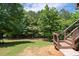 Well-maintained backyard with wooden deck access stairs, lush green grass, and view of the surrounding trees at 344 Nottingham Dr, Marietta, GA 30066