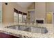 Close up view of stainless double sink, faucet, and granite counter tops with view to breakfast area at 4924 Locklear Way, Marietta, GA 30066