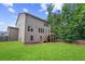 Expansive fenced backyard featuring a lush green lawn, wooden staircase, and a backdrop of trees at 6045 Stargazer Way, Cumming, GA 30028
