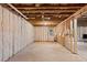 Unfinished basement space with exposed beams and insulation ready for customization with a door to the outside at 6045 Stargazer Way, Cumming, GA 30028
