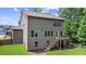View of the back of a two-story home with a wooden deck and stairs, surrounded by a lush green lawn at 6045 Stargazer Way, Cumming, GA 30028
