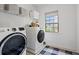 Well-equipped laundry room with modern washer and dryer, storage shelf and natural light from the window at 6045 Stargazer Way, Cumming, GA 30028