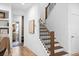 Bright foyer with a wood staircase featuring dark metal balusters and an adjacent entry into a well-lit bathroom at 6045 Stargazer Way, Cumming, GA 30028