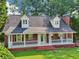 Beautiful brick home featuring a wide front porch, dormer windows, and lush green landscaping at 6841 Fairway Ridge Dr, Douglasville, GA 30134