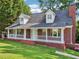 Traditional brick home with a welcoming front porch, dormer windows, and mature trees at 6841 Fairway Ridge Dr, Douglasville, GA 30134