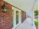 Inviting covered porch featuring a white-painted wood floor, brick pillars, and a charming outdoor light at 6841 Fairway Ridge Dr, Douglasville, GA 30134